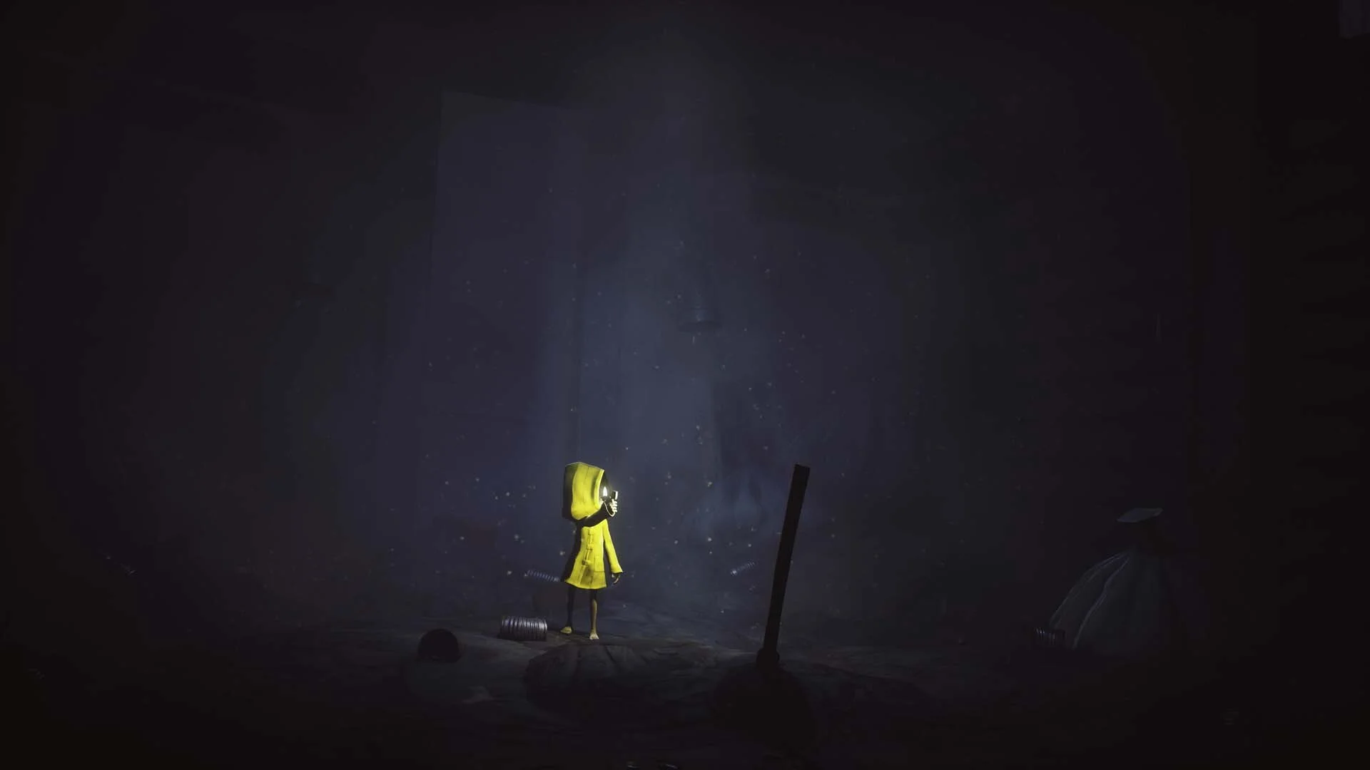 Little Nightmares gameplay showing Six in a yellow raincoat creeping under massive wooden tables in a shadowy kitchen